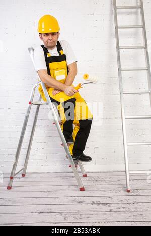 Un pittore professionista compatto e pronto a lavorare in qualsiasi momento. Indossa i tipici indumenti protettivi utilizzati nel cantiere. Foto Stock