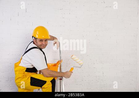 Un pittore professionista compatto e pronto a lavorare in qualsiasi momento. Indossa i tipici indumenti protettivi utilizzati nel cantiere. Foto Stock