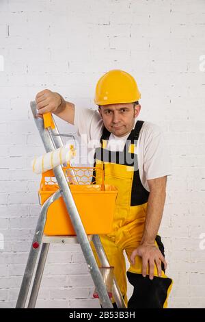 Un pittore professionista compatto e pronto a lavorare in qualsiasi momento. Indossa i tipici indumenti protettivi utilizzati nel cantiere. Foto Stock