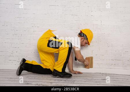 Pittore su un cantiere mentre fa il suo lavoro. È vestito con abiti da lavoro speciali. Foto Stock