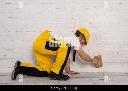 Pittore su un cantiere mentre fa il suo lavoro. È vestito con abiti da lavoro speciali. Foto Stock