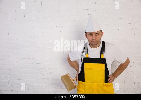 Un pittore professionista compatto e pronto a lavorare in qualsiasi momento. Indossa i tipici indumenti protettivi utilizzati nel cantiere. Foto Stock
