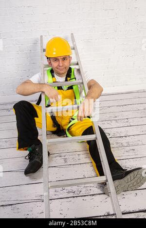 Un pittore professionista compatto e pronto a lavorare in qualsiasi momento. Indossa i tipici indumenti protettivi utilizzati nel cantiere. Foto Stock