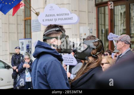 Bucarest, Romania - 4 marzo 2020: Coppia con maschere a gas per protestare contro l'inquinamento atmosferico estremo, di fronte al Ministero dell'ambiente, in B. Foto Stock