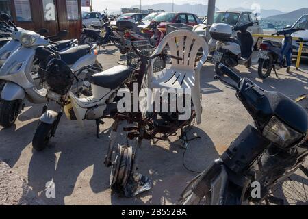 Scooter neri sporchi sul parcheggio con una sedia di plastica bianca sopra di esso Foto Stock