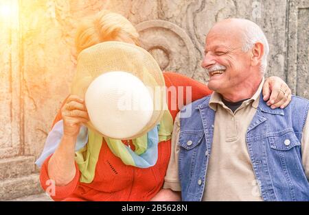 Coppia senior divertirsi mentre la moglie copre il viso dal sole con cappello di moda retrò - Gioioso stile di vita attivo anziani nella città vecchia concorso - Lov Foto Stock