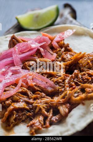 Tacos Messicano di Cochinita Pibil, maiale marinato arrostito alla fossa, servito con salsa habanero in stile Yucatan e cipolle rosa sottaceto Foto Stock