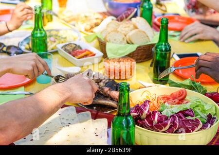 Multi gara amici mangiare barbecue all'aperto nel cortile - giovani che hanno pasto e tostare le birre in estate - amicizia e concetto di cibo - Così Foto Stock