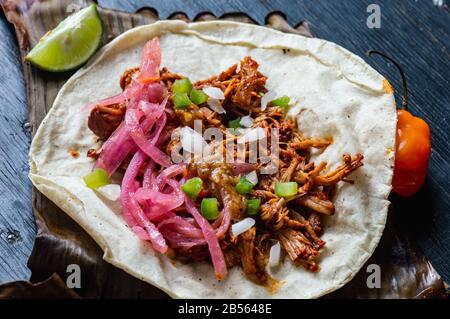 Tacos Messicano di Cochinita Pibil, maiale marinato arrostito alla fossa, servito con salsa habanero in stile Yucatan e cipolle rosa sottaceto Foto Stock