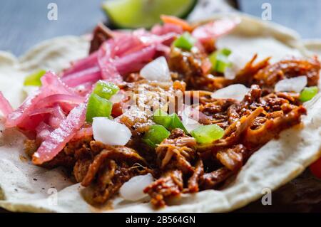 Tacos Messicano di Cochinita Pibil, maiale marinato arrostito alla fossa, servito con salsa habanero in stile Yucatan e cipolle rosa sottaceto Foto Stock