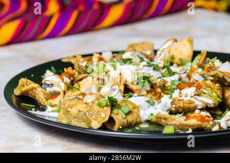 Chilaquiles verde, tradizionale cibo vegetariano messicano per la colazione a base di tortillas fritte e condito con salsa verde Foto Stock