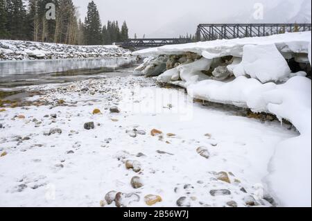 Giornata di neve al ponte motore pedonale che attraversa il fiume Bow a Canmore, Alberta, Canada Foto Stock