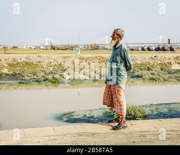 Chittagong, Bangladesh, 22 dicembre 2017: Ritratto di un vecchio pescatore con il ponte Shan Amanat sul fiume Karnafuli sullo sfondo Foto Stock