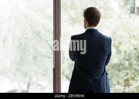 Vista posteriore di imprenditore cercare nel pensiero di distanza Foto Stock