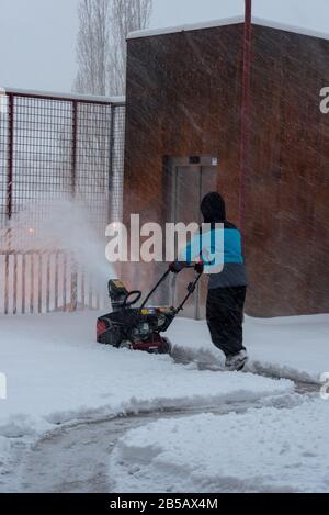 L'uomo rimuove la neve con la macchina in una giornata invernale ad Andorra. Foto Stock