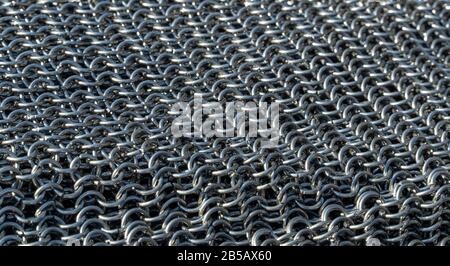 Reale tessitura artigianale della chainmail vicino. Sfondo da anelli metallici, hauberk. Foto Stock