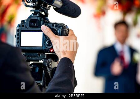 Videografo femmina nella parte posteriore sono shooing e registrazione video in caso di matrimonio. Foto Stock
