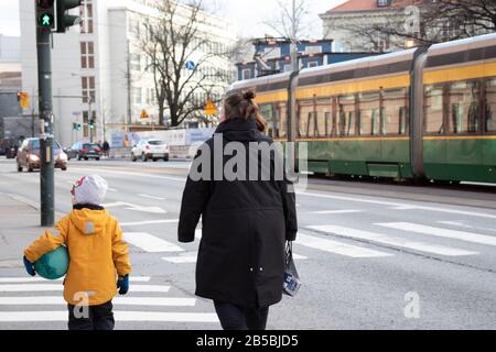 Helsinki, Finlandia - 3 marzo 2020: Donna con bambino che cammina per strada, editoriale Illustrativo Foto Stock