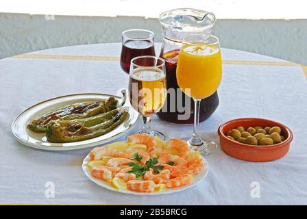 Una selezione di tapas con sangria e birra, peperoni verdi fritti, cocktail di olive, gamberi al limone, Costa del Sol, Provincia di Malaga, Andalusia, Spagna, Foto Stock