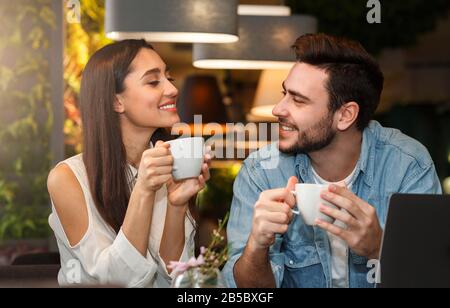 Giovane coppia degustazione caffè godendo flirt e conversazione in caffetteria Foto Stock