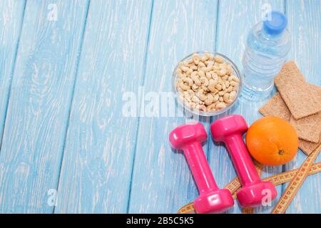 Il concetto di mangiare sano. Manubri piccoli, noci, bottiglia d'acqua, stile di vita sano. Sport fitness cibo Foto Stock