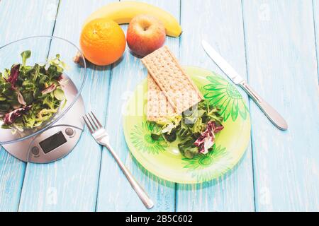 Deliziosa insalata di erbe verdi su un piatto, bilancia da cucina. Il concetto di nutrizione adeguata. Dieta. Foto Stock