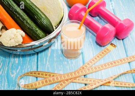 Bicchieri con succhi di verdure fresche e manubri sul tavolo Foto Stock
