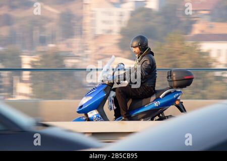 Belgrado, Serbia - 25 Ottobre 2019 : un uomo che guida uno scooter blu nel traffico sulla strada della città, panoramica shot Foto Stock