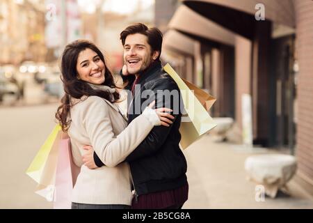 Giovane coppia amorevole che trasporta i sacchetti di shopping della carta Foto Stock