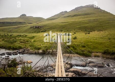 Ponte sospeso a corda stretta che attraversa il fiume Pholela presso il campeggio Cobham nel sud di Drakensberg, Sudafrica Foto Stock