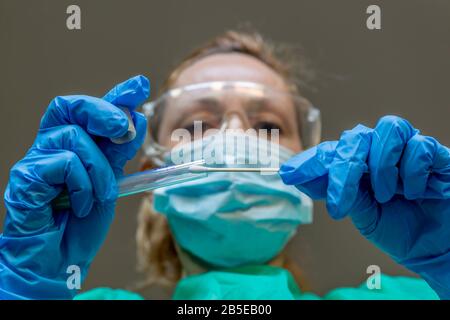 Una donna bianca bionda che lavora come tecnico di laboratorio esegue un tampone per verificare la presenza di una possibile infezione da Coronavirus Covid-19 Foto Stock