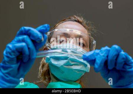 Una donna bianca bionda che lavora come tecnico di laboratorio esegue un tampone per verificare la presenza di una possibile infezione da Coronavirus Covid-19 Foto Stock