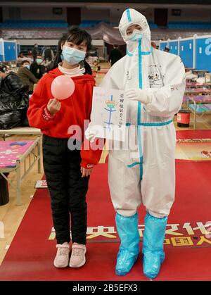 (200308) -- WUHAN, 8 marzo 2020 (Xinhua) -- Liu Jiayu (L) e un operatore medico posano per una foto con la sua pittura in un ospedale improvvisato nel distretto di Wuchang di Wuhan, nella provincia centrale cinese di Hubei, 8 marzo 2020. Nel mese di febbraio, Liu Jiayu, di 11 anni, è stato infettato da una nuova polmonite da coronavirus e ammesso in un ospedale improvvisato nel distretto di Wuchang di Wuhan. In occasione di un evento organizzato da pazienti e operatori sanitari nell'ospedale improvvisato per celebrare la Giornata Internazionale della Donna di domenica, ha presentato la sua pittura per esprimere i suoi buoni auspici ai medici. (Xinhua/Wang Yuguo) Foto Stock