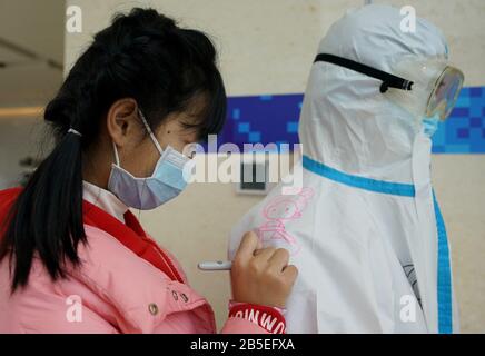 (200308) -- WUHAN, 8 marzo 2020 (Xinhua) -- Liu Jiayu dipinge sul vestito protettivo di un operatore medico in un ospedale improvvisato nel distretto di Wuchang, nella provincia centrale cinese di Hubei, 8 marzo 2020. Nel mese di febbraio, Liu Jiayu, di 11 anni, è stato infettato da una nuova polmonite da coronavirus e ammesso in un ospedale improvvisato nel distretto di Wuchang di Wuhan. In occasione di un evento organizzato da pazienti e operatori sanitari nell'ospedale improvvisato per celebrare la Giornata Internazionale della Donna di domenica, ha presentato la sua pittura per esprimere i suoi buoni auspici ai medici. (Xinhua/Wang Yuguo) Foto Stock