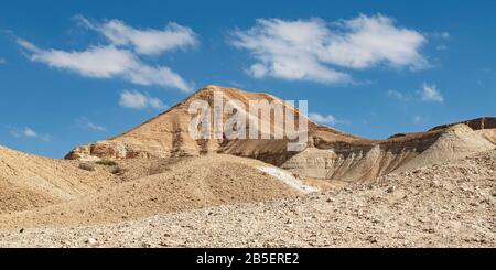 La collina a forma di cono conosciuta come keren akev sorge sopra il letto del torrente nahal akev nella valle di zin vicino a Sde Boker in Israele con un blu chiaro parzialmente nuvoloso Foto Stock