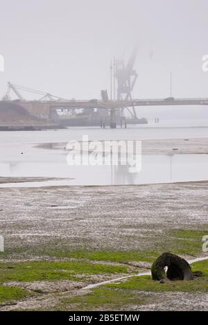 Ammira Ports Creek da Alexandra Park, Portsmouth, Hampshire, Inghilterra, guardando verso Pounds Yard, Tipner, con una gru avvolta in una nuvola bassa. Foto Stock