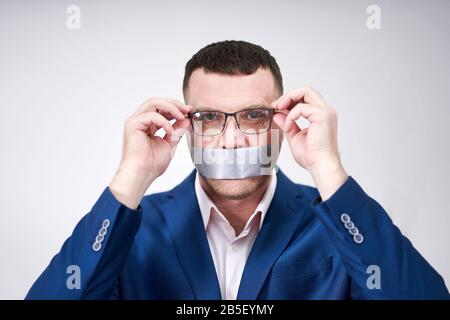 l'uomo ha un grande pezzo di nastro industriale nero che copre la sua bocca, concetto di silenzio Foto Stock