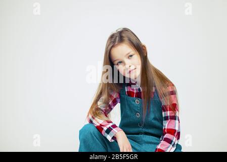 Ritratto di una bambina in jeans e una camicia in plaid. Studio fotografia di moda Foto Stock