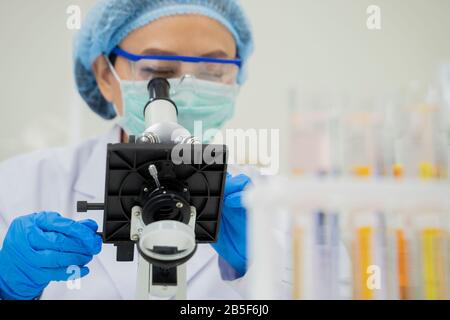 Gli scienziati lavorano e guardano i microscopi nei laboratori per sviluppare vaccini contro i virus. Foto Stock