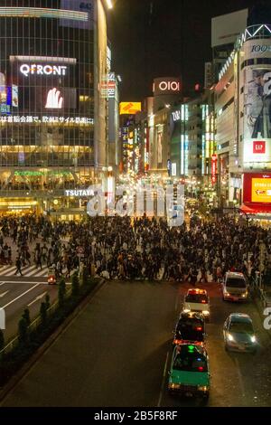 Fotografia notturna di un coronamento di pedoni che attraversa un incrocio a quattro vie zebra al passaggio Shibuya nel centro di Tokyo, Giappone Foto Stock