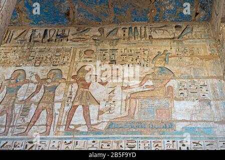 Hieroglypic dipinti sculture sul muro presso l'antico tempio egiziano di Medinat Habu a Luxor Foto Stock