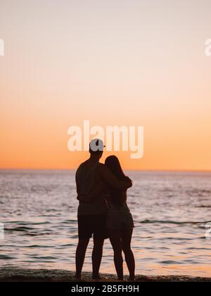 Alcune sagome di persone si sono riunite sulla riva di a. spiaggia al tramonto in Australia Foto Stock