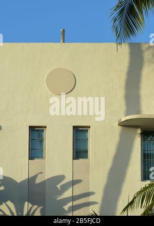 Semplice, gemometrico art deco a Miami, Florida. Finestre rettangolari, cerchio ornamentale e ombre di palme su pareti di stucco giallo. Foto Stock