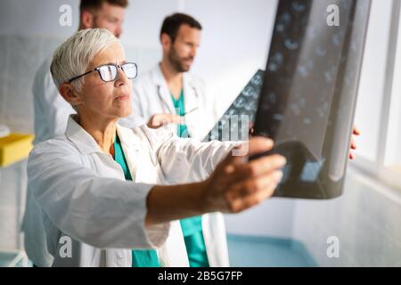 Gruppo di medici che esaminano una radiografia in ospedale per fare diagnosi Foto Stock