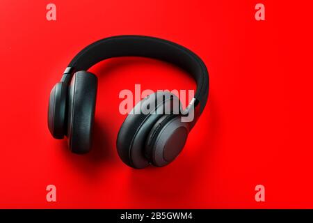 Cuffie wireless nere su sfondo rosso. Cuffie isolate di livello professionale per DJ e musicisti. Vista dall'alto. Foto Stock