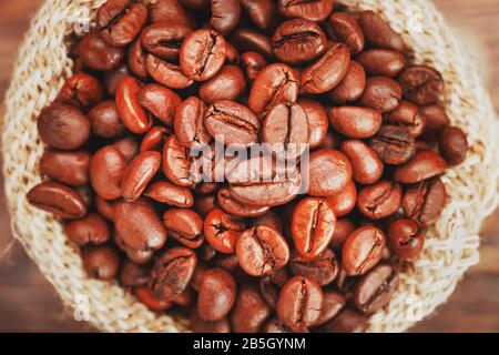 Chicchi di caffè in un sacchetto di burlap su uno sfondo di legno. Chicchi di caffè arrostiti Aromatici a contrasto morbido. La vista dall'alto. Foto Stock