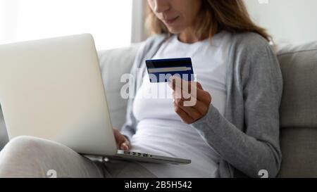 Giovane donna che acquista su un portatile a casa online Foto Stock