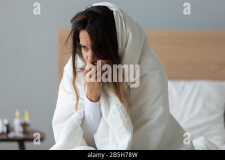 Giovane donna malata avvolta in coperta si sente male Foto Stock