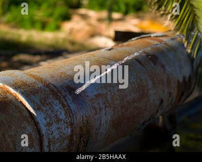 Un tubo di irrigazione che è così vecchio e arrugginito che ha mollato una perdita di gushing. Foto Stock