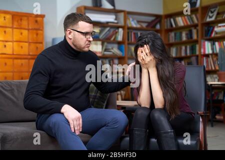 Giovane donna allo psicologo, sentendosi disperata e depressa, piangendo tenendo la testa nelle mani, sconvolta la ragazza adolescente Foto Stock